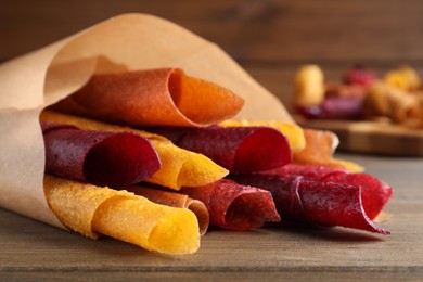 Photo of Delicious fruit leather rolls on wooden table, closeup
