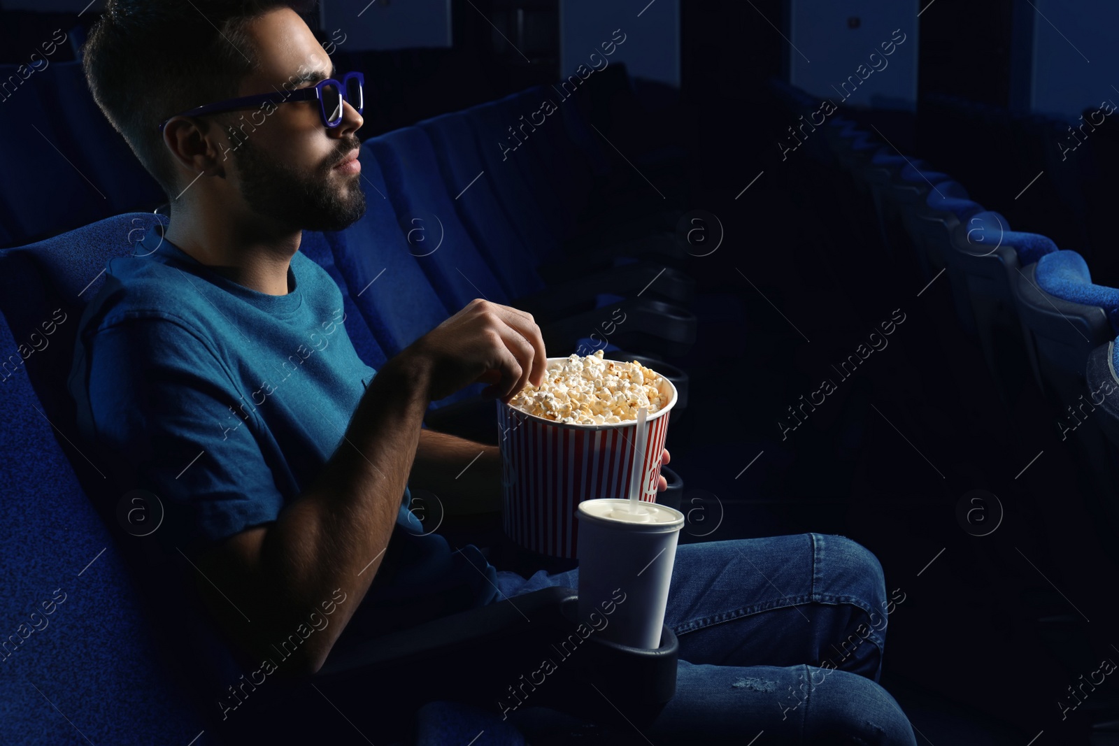 Photo of Young man with popcorn watching movie in cinema