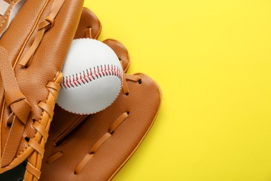 Photo of Catcher's mitt and baseball ball on yellow background, top view with space for text. Sports game