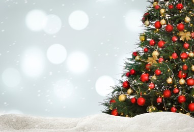 Image of Beautifully decorated Christmas tree and snow on light background, space for text. Bokeh effect