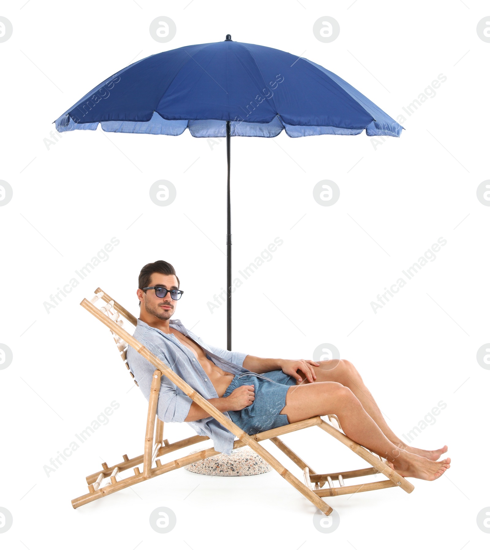 Photo of Young man on sun lounger under umbrella against white background. Beach accessories