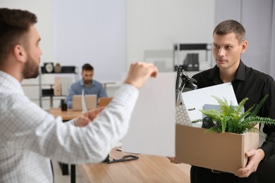 Photo of Boss with paper sheet dismissing man from work in office