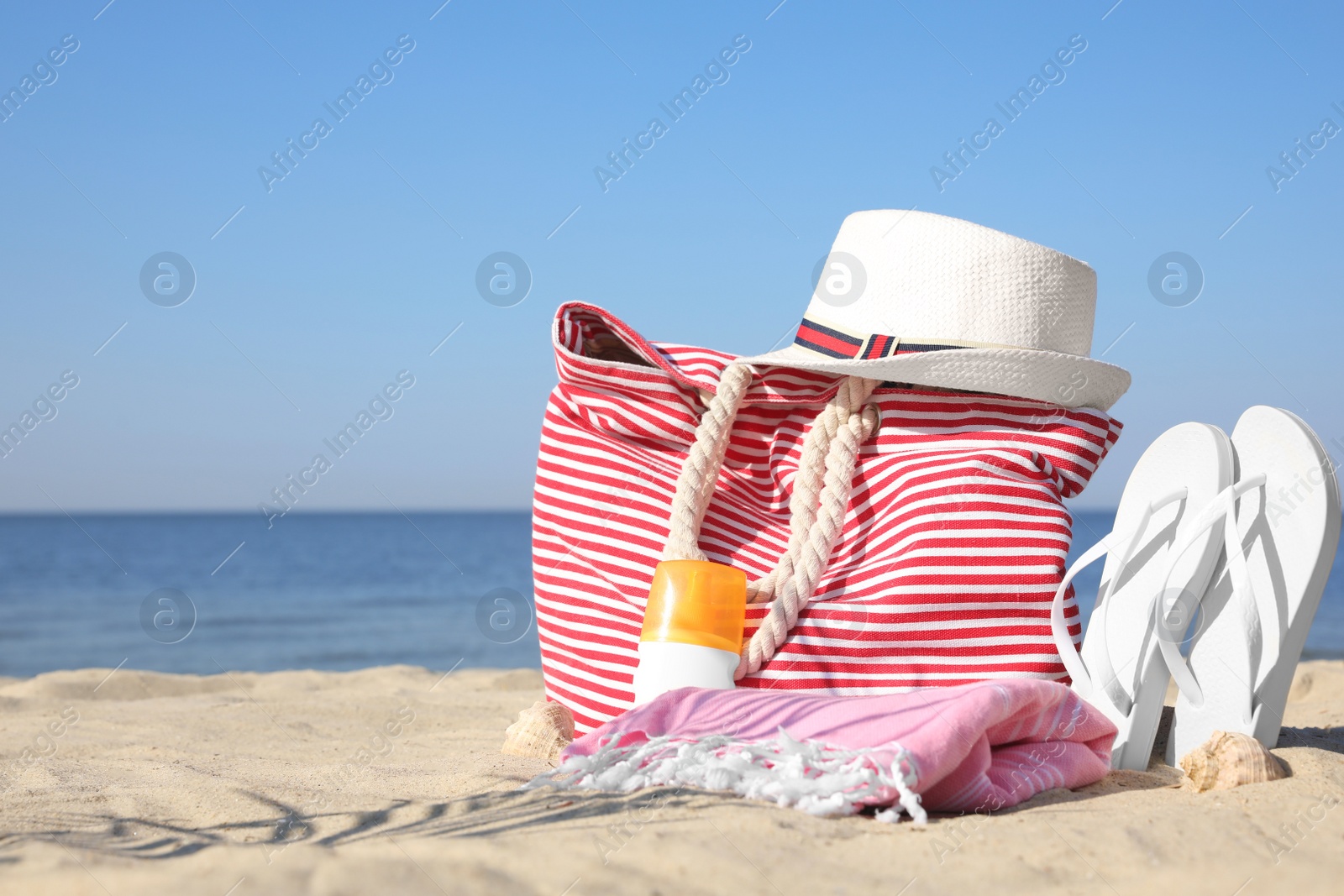 Photo of Stylish beach accessories on sandy sea shore