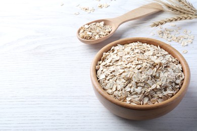 Photo of Oatmeal, bowl and spoon on white wooden table. Space for text