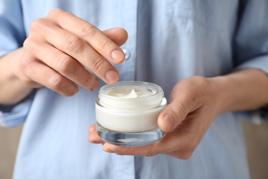 Photo of Woman holding glass jar of cream, closeup