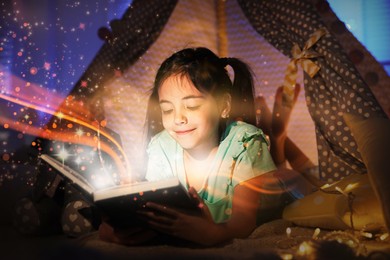 Image of Little girl reading fairy tale in play tent at home