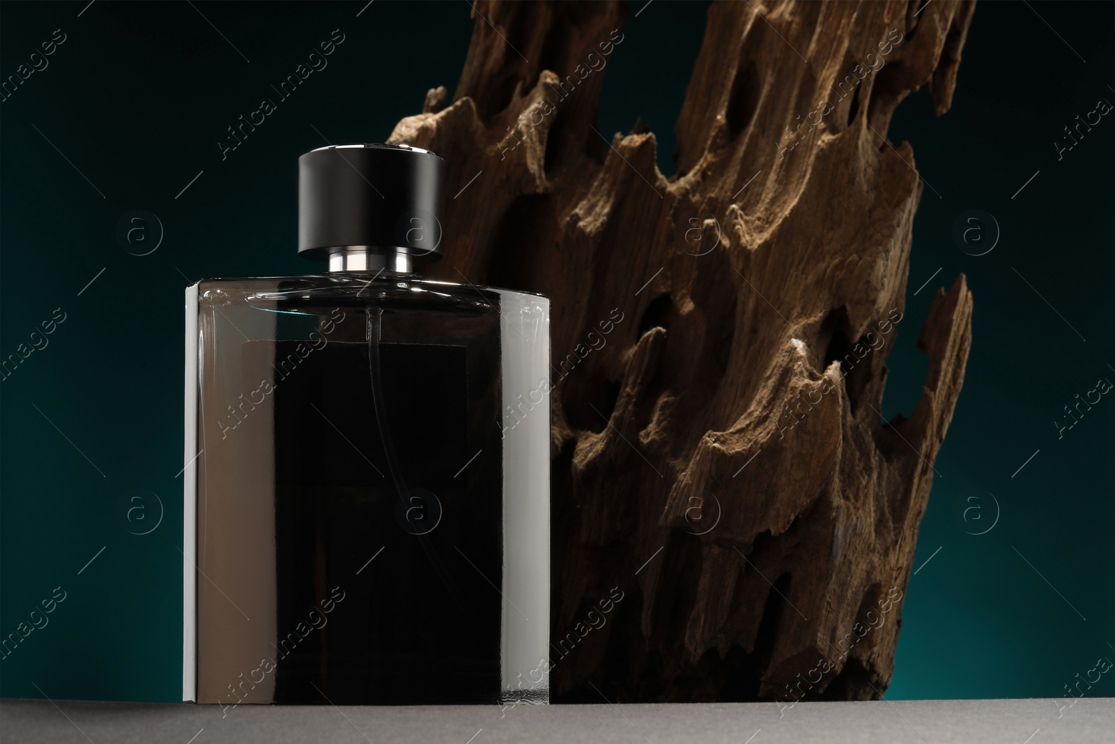 Photo of Luxury men`s perfume in bottle on grey table against color background, space for text