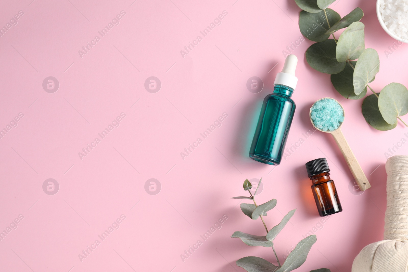 Photo of Different aromatherapy products and eucalyptus branches on pink background, flat lay. Space for text