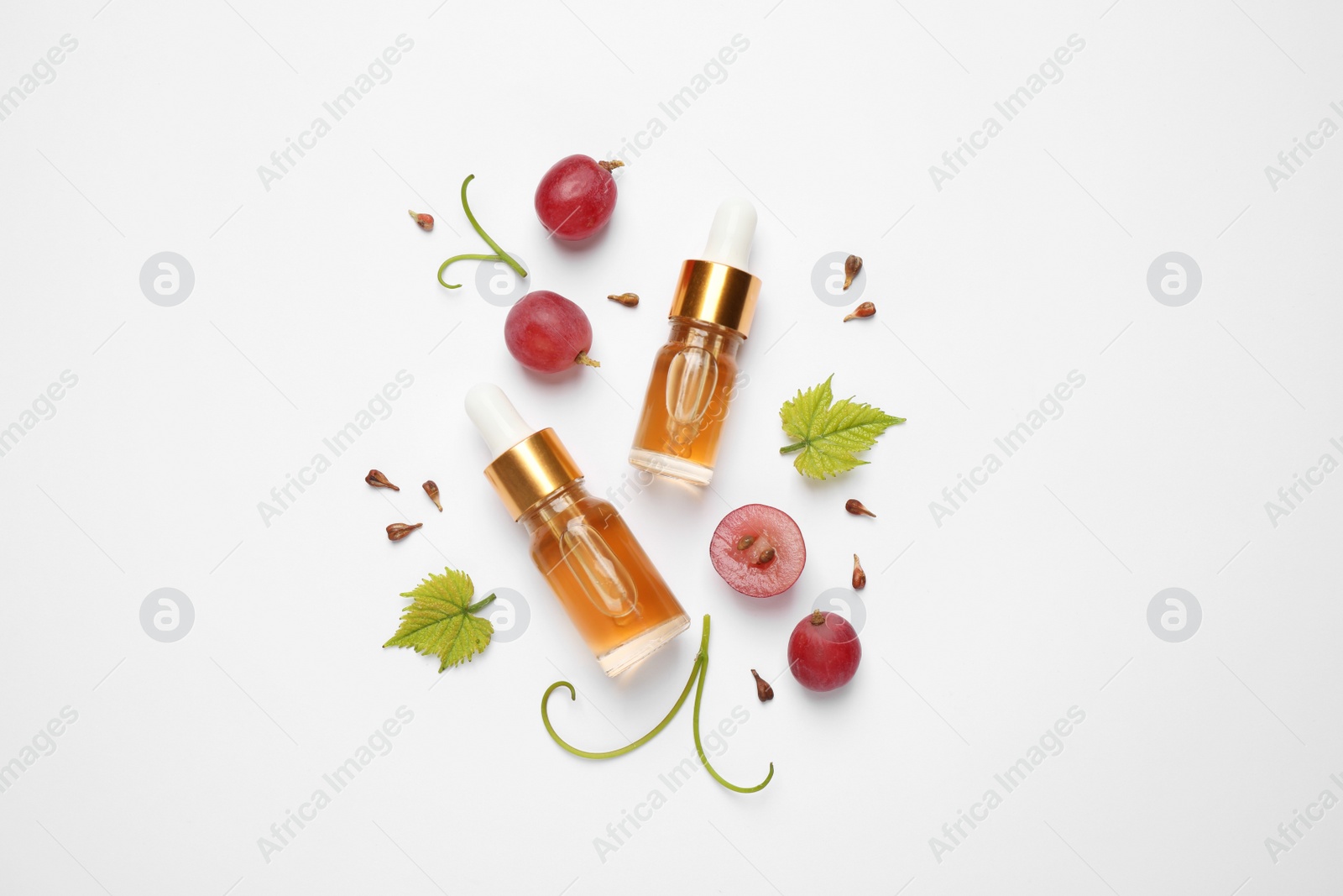 Photo of Flat lay composition with natural grape seed essential oil on white background. Organic cosmetics