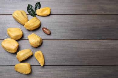 Delicious exotic jackfruit bulbs on wooden table, flat lay. Space for text