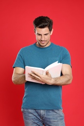 Handsome man reading book on color background