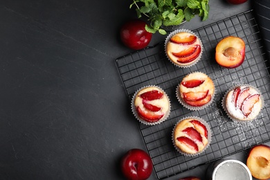 Delicious cupcakes with plums on black table, flat lay. Space for text