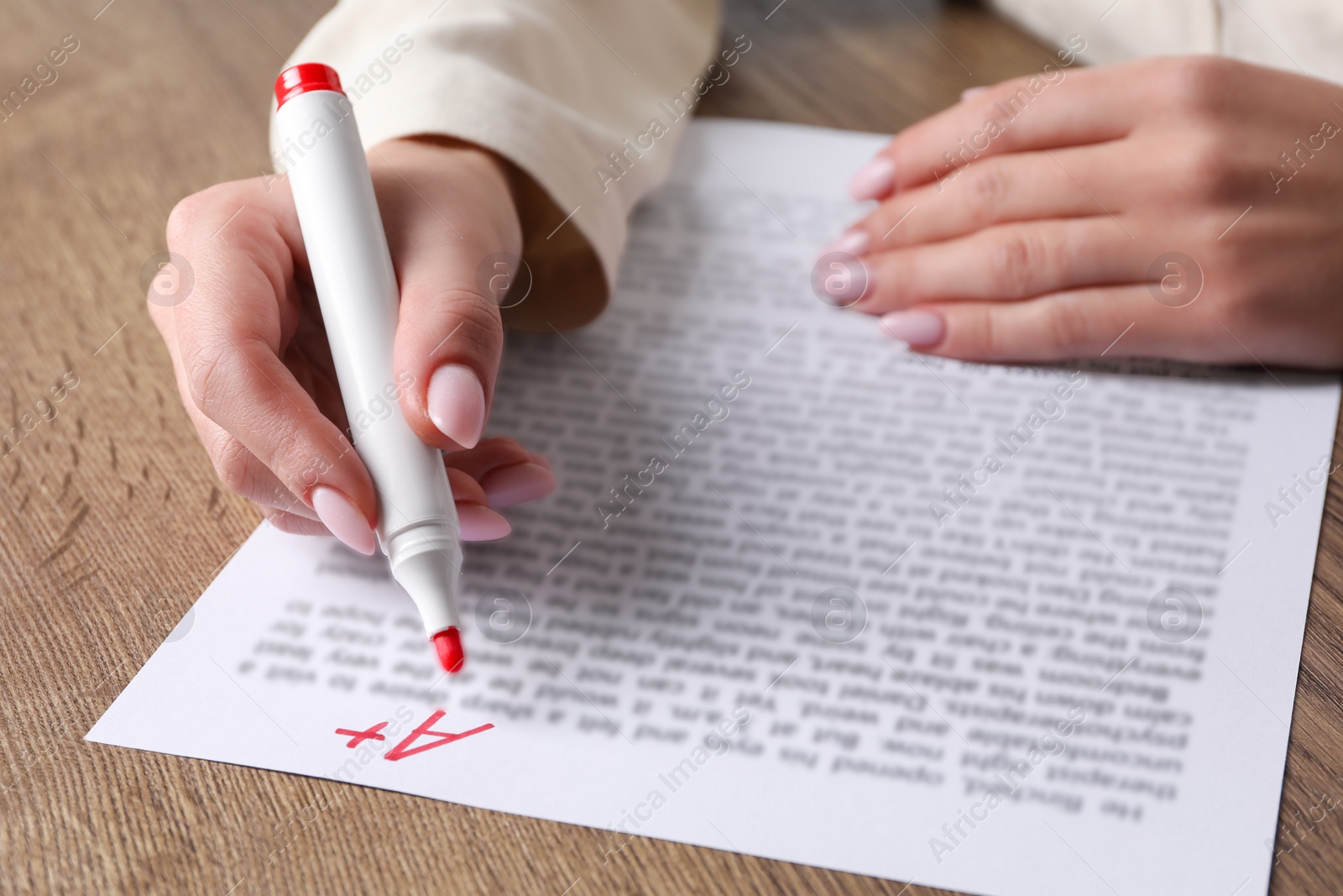 Photo of School grade. Teacher writing letter A with plus symbol on sheet of paper at wooden table, closeup