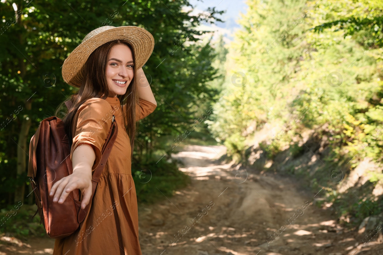 Photo of Happy woman with backpack and hat enjoying her walk in forest