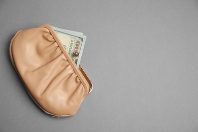 Photo of Stylish beige leather purse with dollar banknotes on light grey background, top view. Space for text