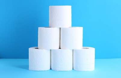 Photo of Pyramid of toilet paper rolls on light blue background