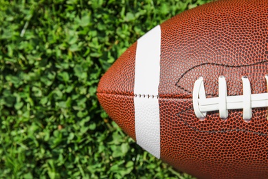 Photo of Ball for American football on fresh green field grass, top view