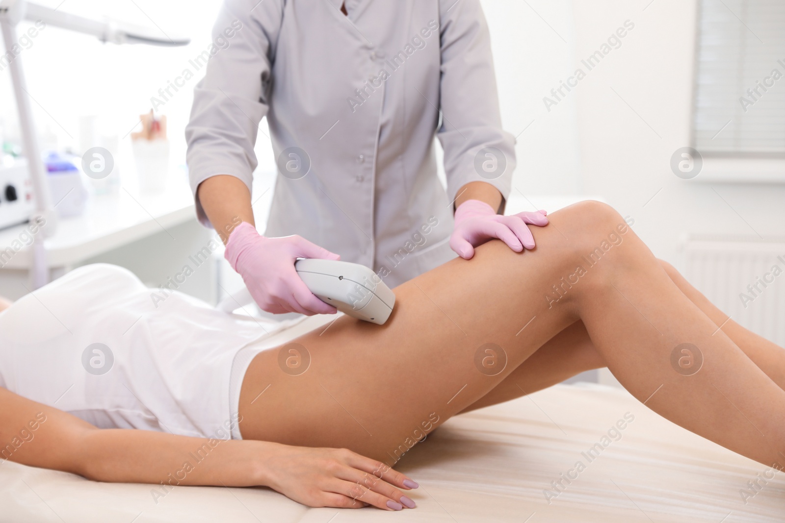 Photo of Young woman undergoing laser epilation procedure in beauty salon, closeup