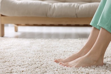 Woman on soft light brown carpet at home, closeup. Space for text