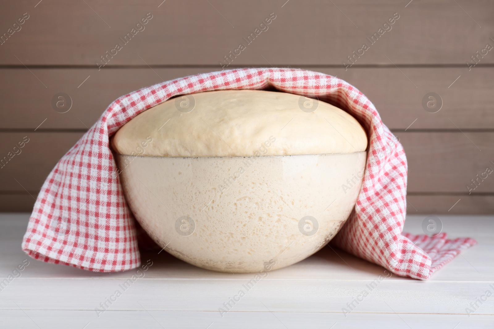 Photo of Bowl of fresh yeast dough on white wooden table