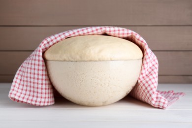 Bowl of fresh yeast dough on white wooden table