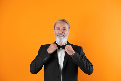 Photo of Handsome bearded mature man in suit on color background