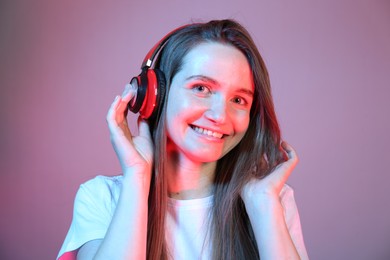 Portrait of beautiful woman with headphones in neon lights on color background