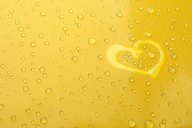 Photo of Heart shape of water and drops on yellow background