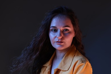 Portrait of beautiful young woman on color background with neon lights