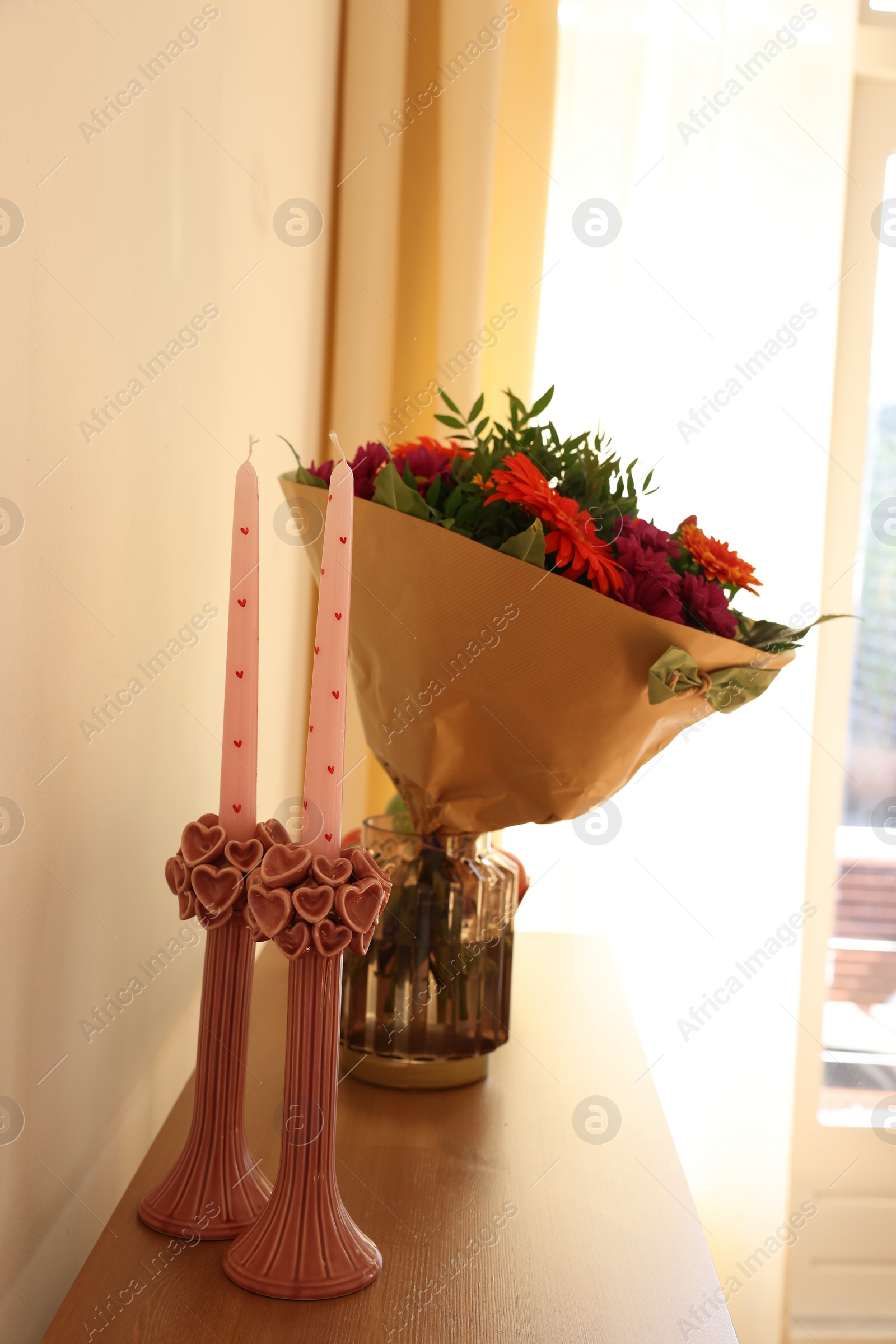 Photo of Bouquet of flowers and candles on wooden table indoors