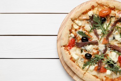 Tasty pizza with anchovies, arugula and olives on white wooden table, top view. Space for text