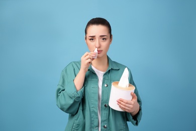 Photo of Woman using nasal spray on light blue background