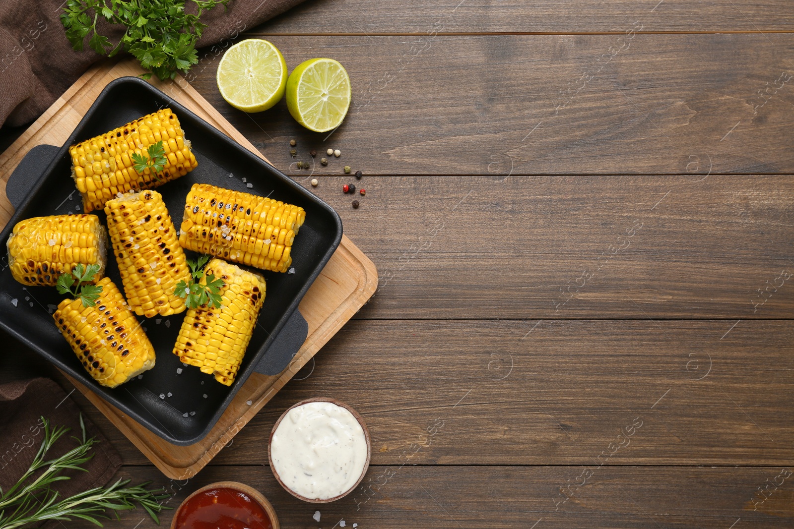 Photo of Flat lay composition with tasty grilled corn on wooden table. Space for text