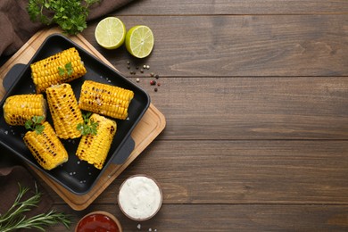 Photo of Flat lay composition with tasty grilled corn on wooden table. Space for text