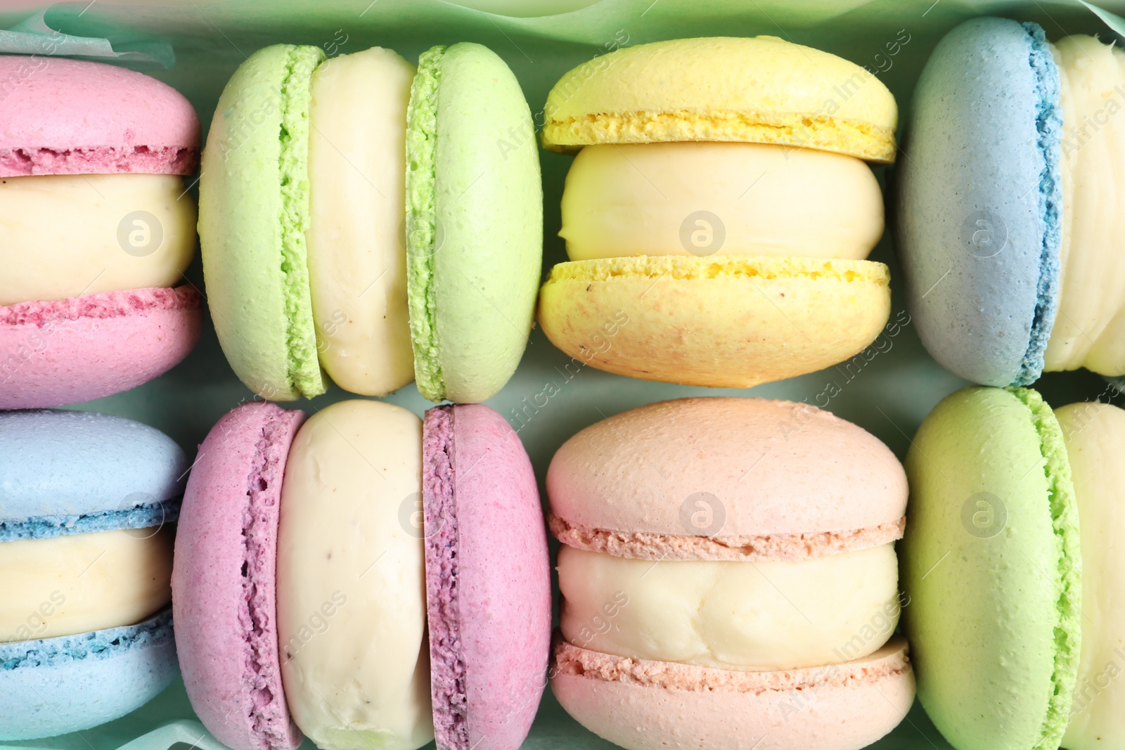 Photo of Many delicious colorful macarons in box, top view