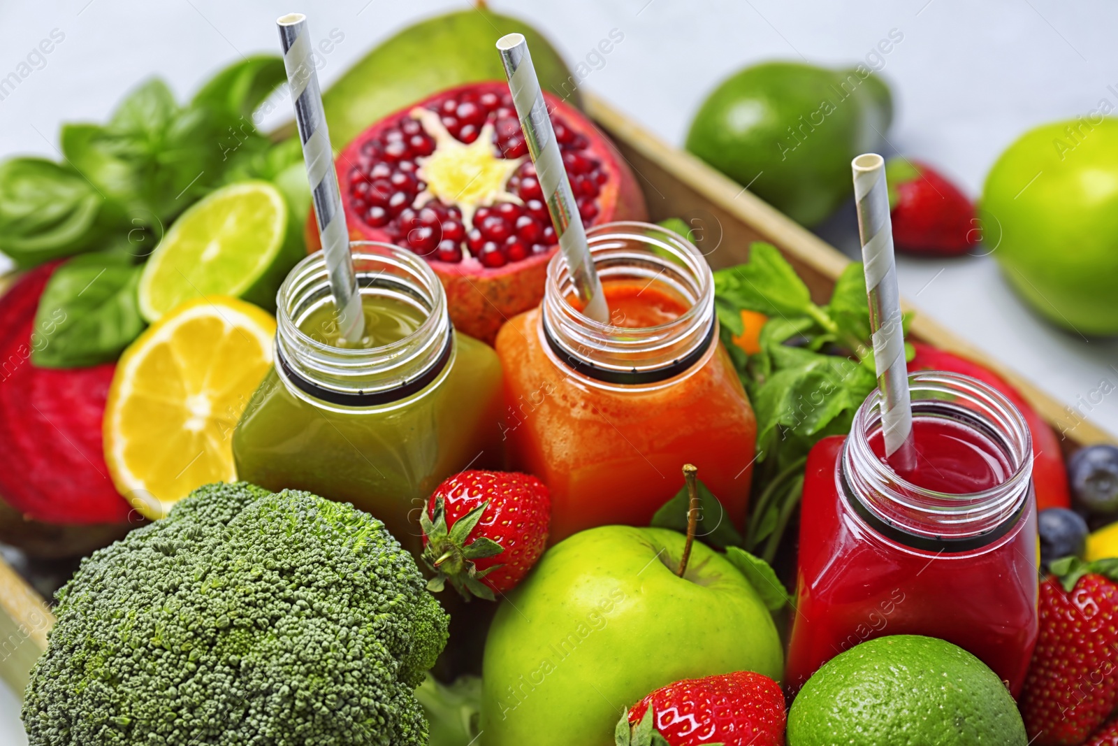 Photo of Bottles with healthy detox smoothies and ingredients in crate, closeup