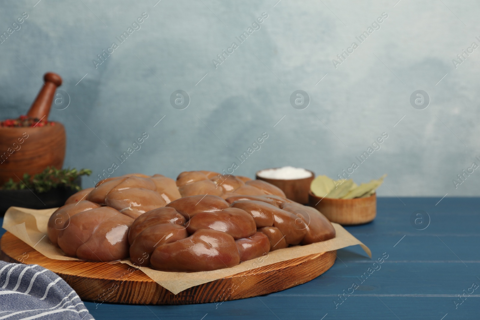 Photo of Fresh raw kidney meat on blue wooden table, space for text