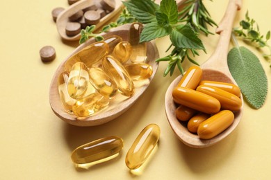Photo of Different pills and herbs on light yellow background, closeup. Dietary supplements