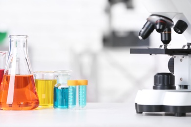 Different glassware with samples and microscope on table in chemistry laboratory