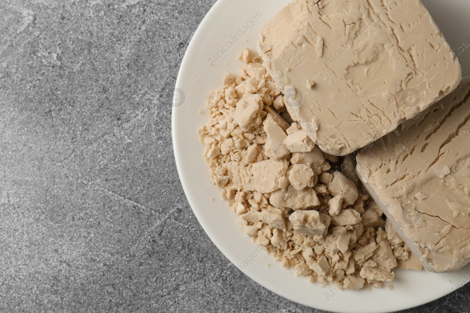 Photo of Compressed yeast on grey table, top view. Space for text