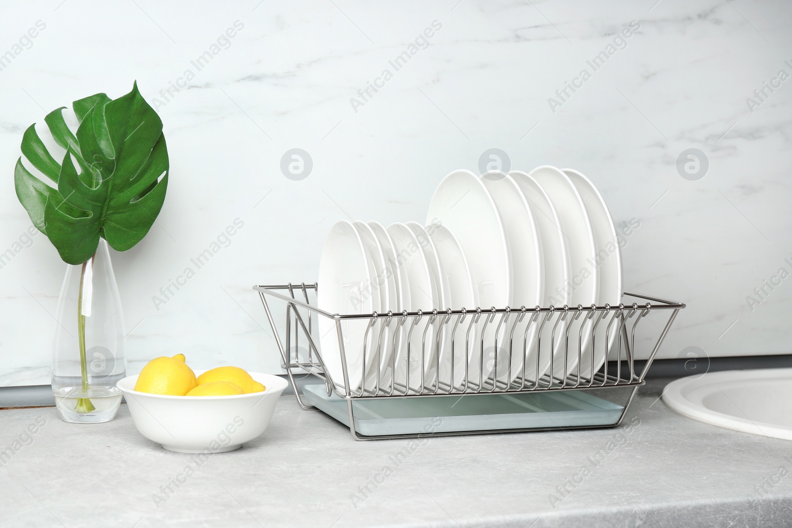 Photo of Different clean plates in dish drying rack on kitchen counter