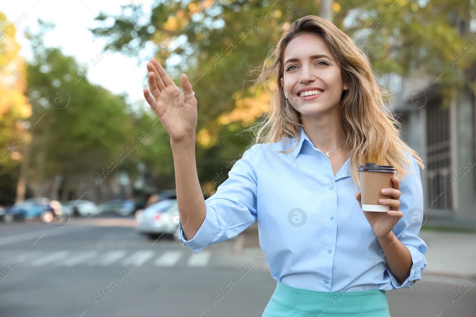 Photo of Young businesswoman catching taxi on city street