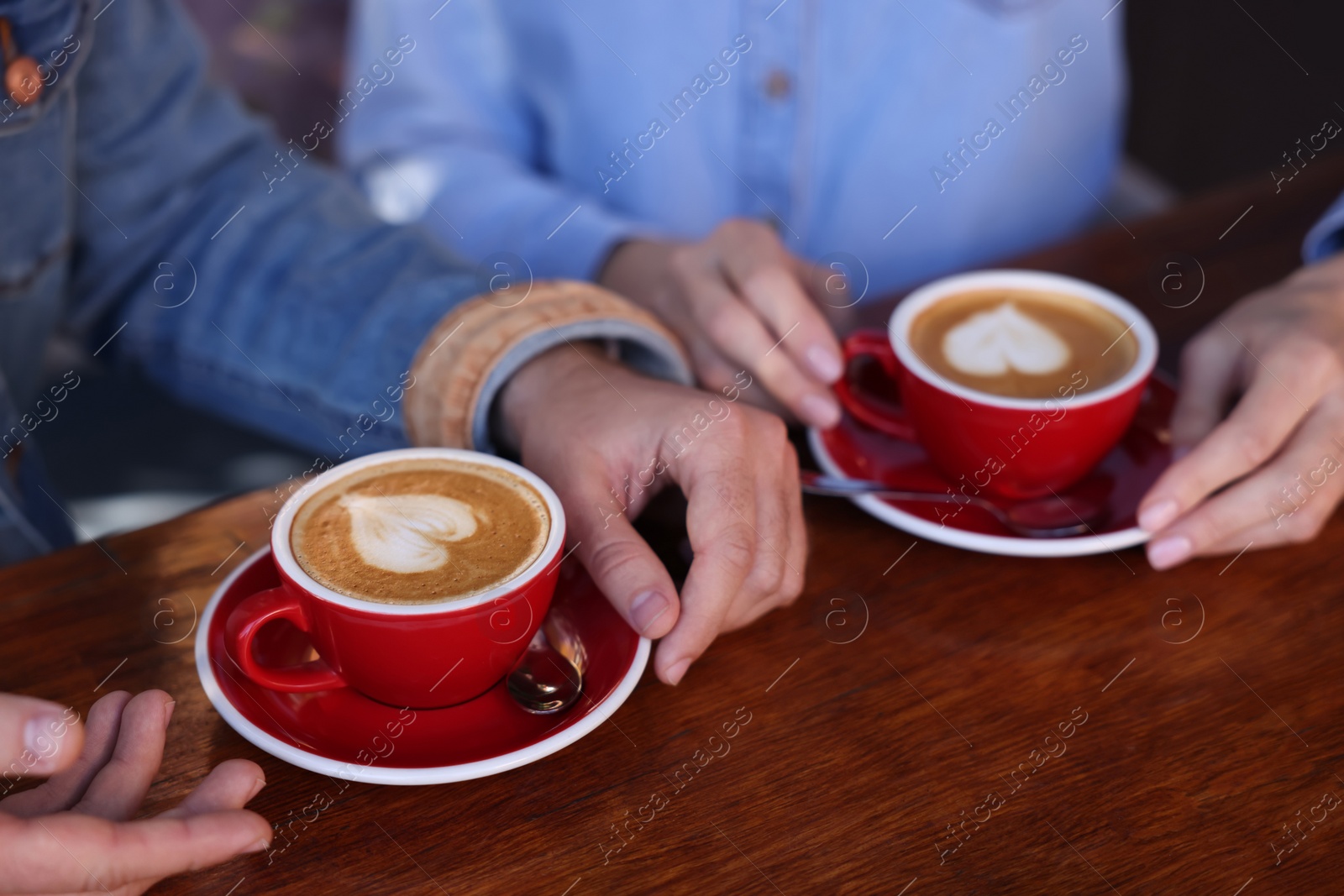 Photo of Couple with cups of aromatic coffee at wooden table, closeup