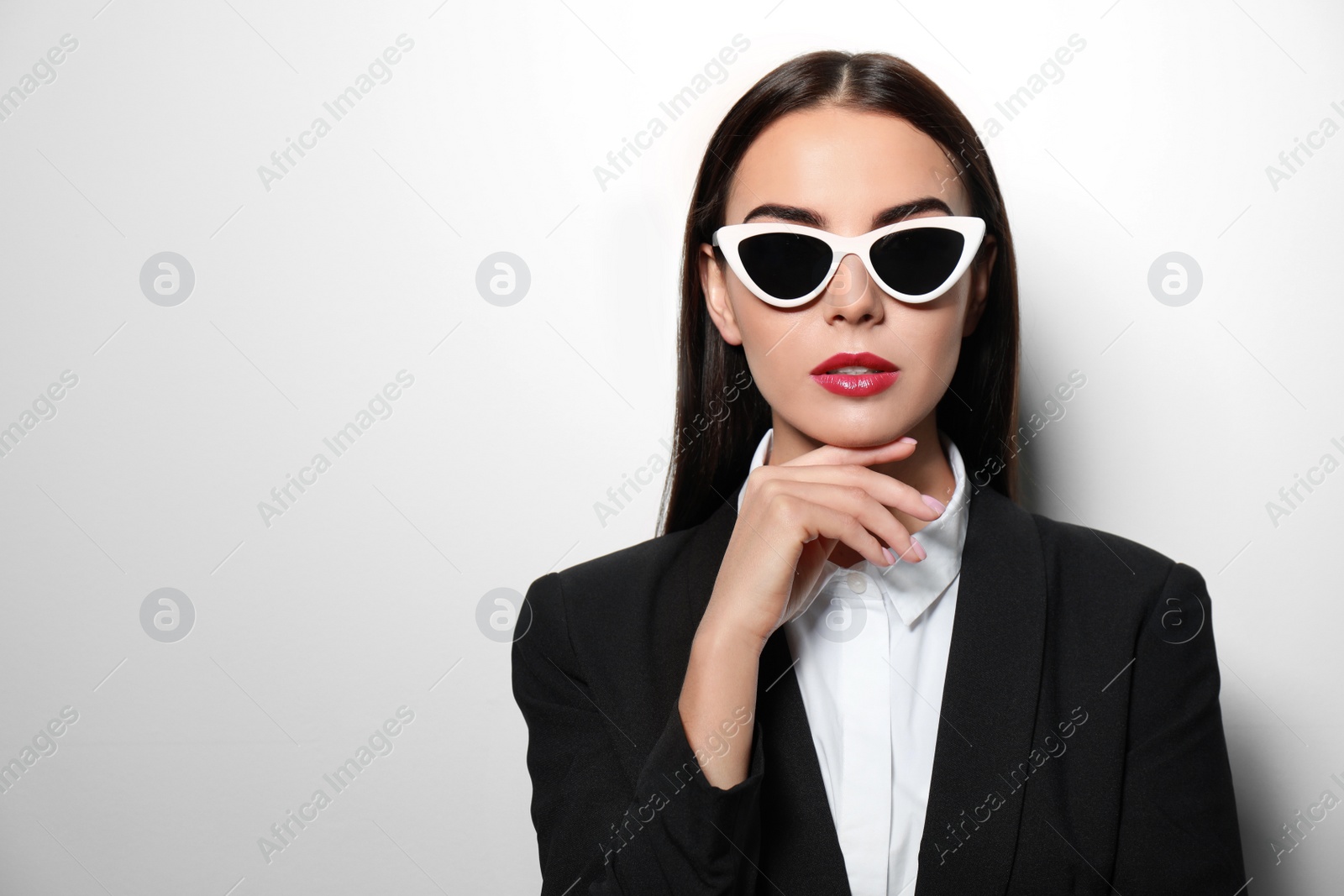 Photo of Young businesswoman in stylish sunglasses on light background, space for text