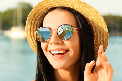 Image of Happy woman on vacation. Sun loungers and ocean mirroring in her sunglasses