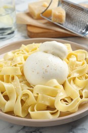 Photo of Delicious pasta with burrata cheese on white marble table, closeup