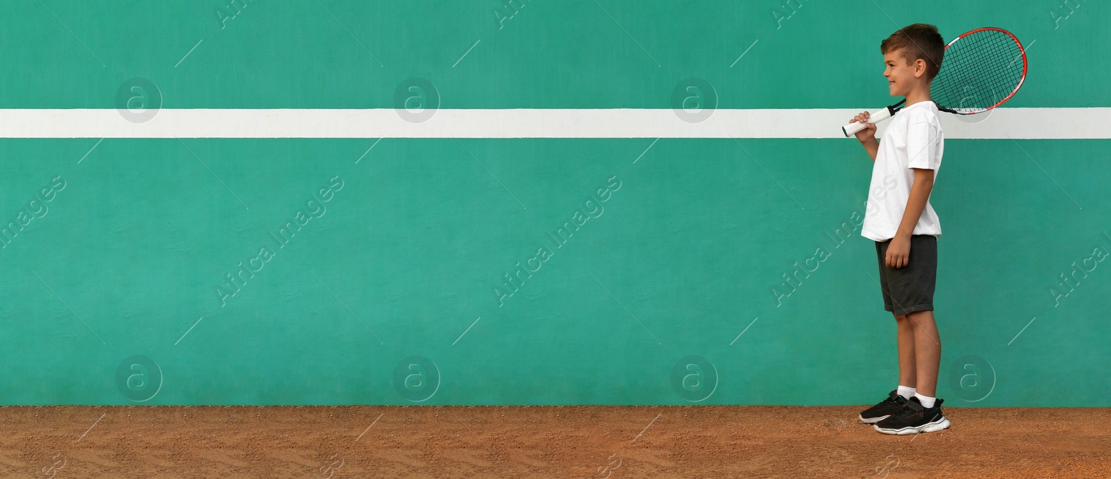 Image of Cute little boy near green wall on tennis court. Banner design with space for text