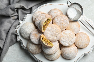 Photo of Traditional cookies for Islamic holidays and strainer with powdered sugar on table, top view. Eid Mubarak