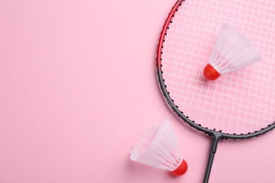 Photo of Badminton racket and shuttlecocks on pink background, flat lay. Space for text