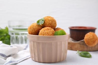 Photo of Bowl of delicious fried tofu balls with basil on white table